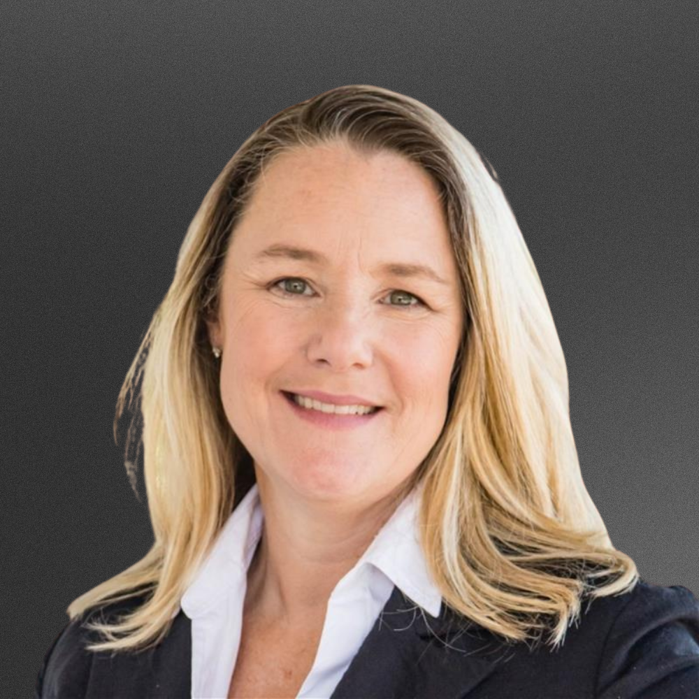 Blonde woman in black blazer with white button down underneath.